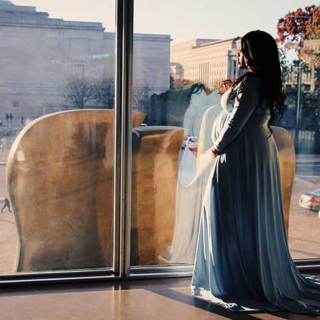 Pregnant woman standing at a window.